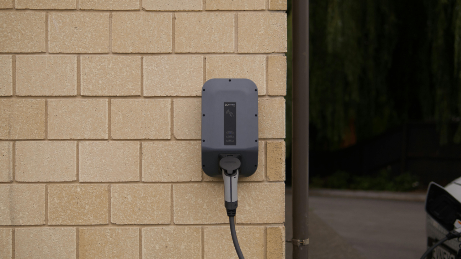 Home EV charger mounted on an exterior brick wall in Crewe